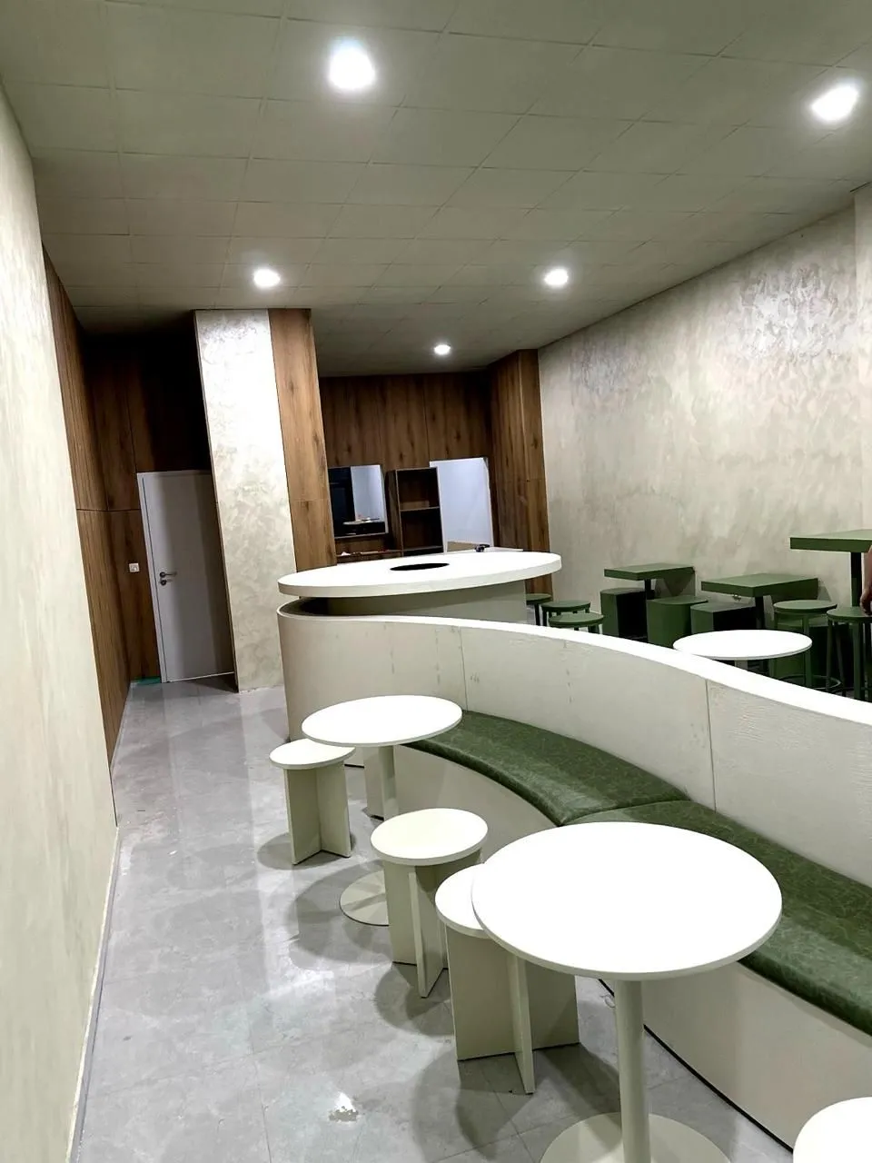 Lounge de bureaux à Genève, banquette verte et tables rondes blanches