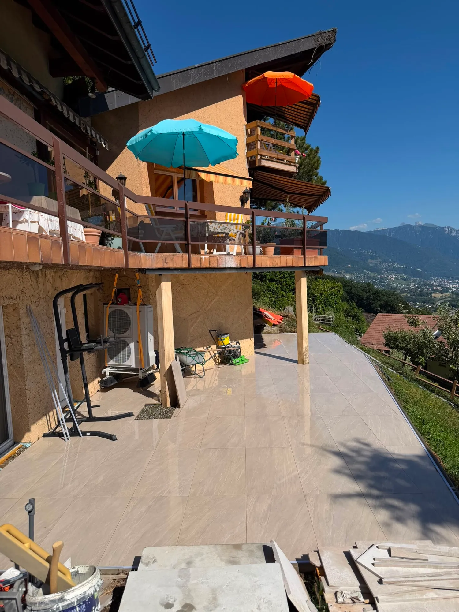 Terrasse en dalles de grès cérame beige devant une maison à Jongny, vue sur le lac Léman et les montagnes