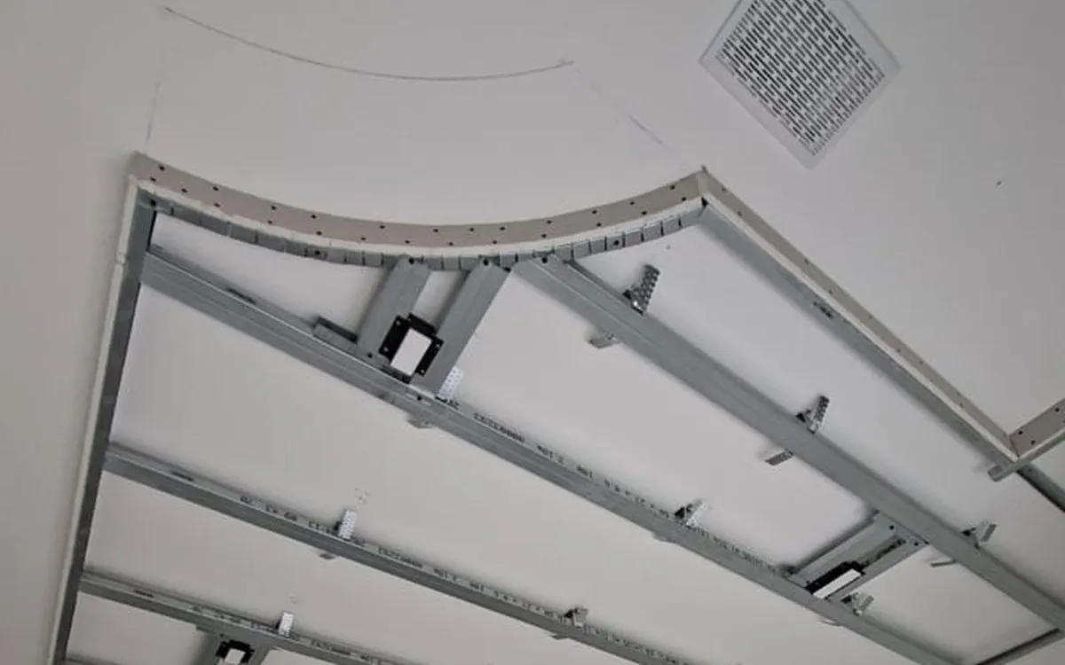 Ossature métallique d’un faux-plafond en courbe, avant la pose des plaques, à Rolle