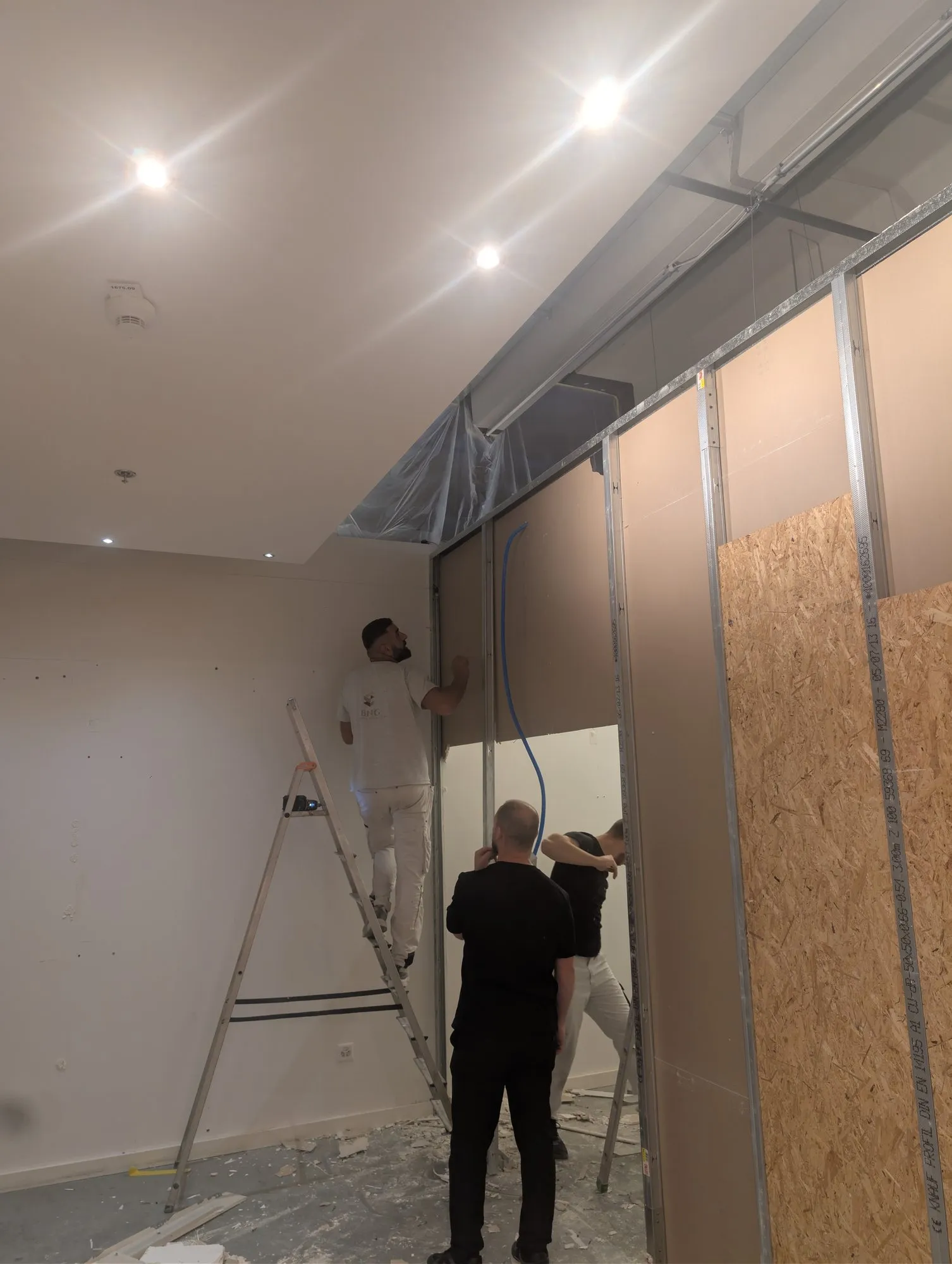 Montage des cloisons derrière la palissade de chantier
