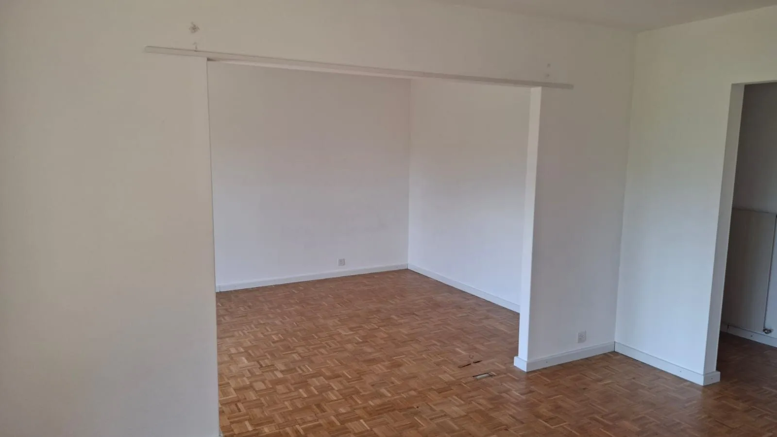 Séjour vide de la villa, murs blancs et parquet