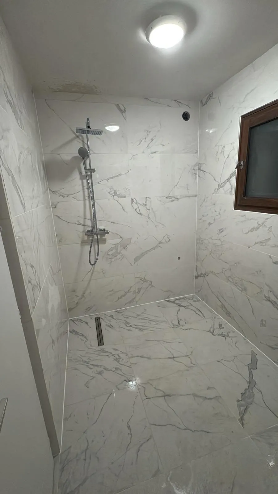 Douche de plain-pied carrelée de marbre blanc dans une salle de bain à Genève