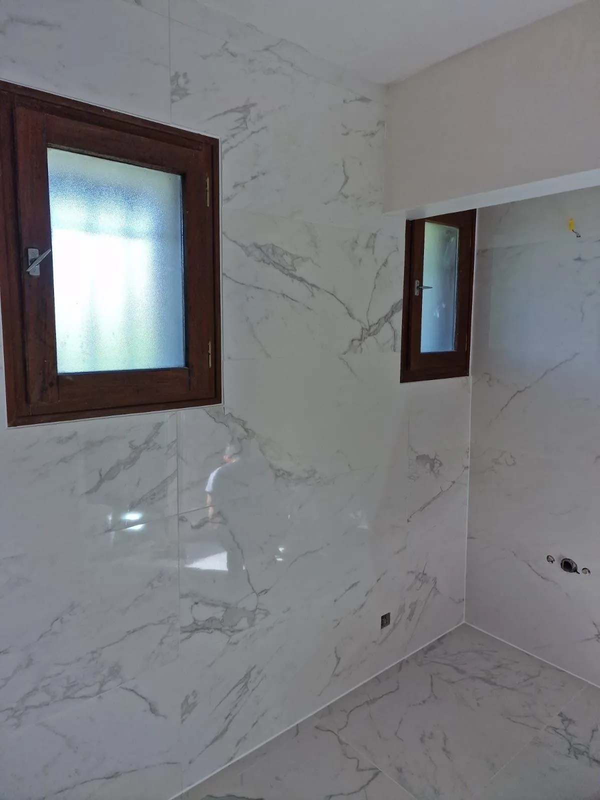 Douche de plain-pied carrelée de marbre blanc, avec une petite fenêtre