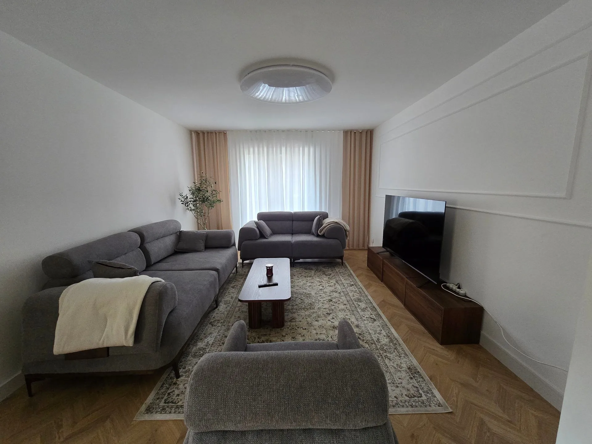 Salon d’un appartement à Nyon, murs à moulures repeints en blanc et parquet en chevrons