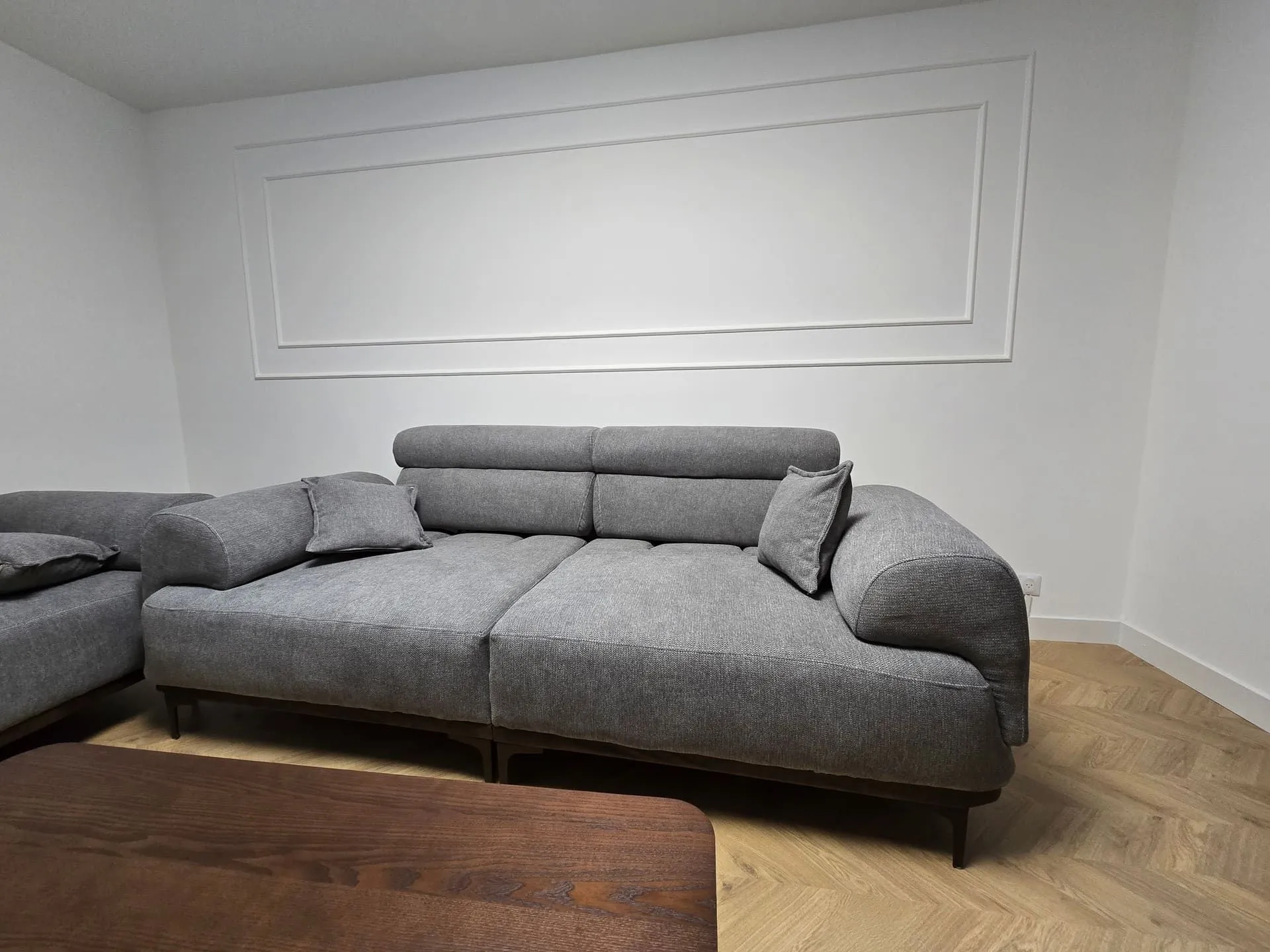 Salon d’un appartement à Nyon, murs à moulures repeints en blanc et parquet en chevrons