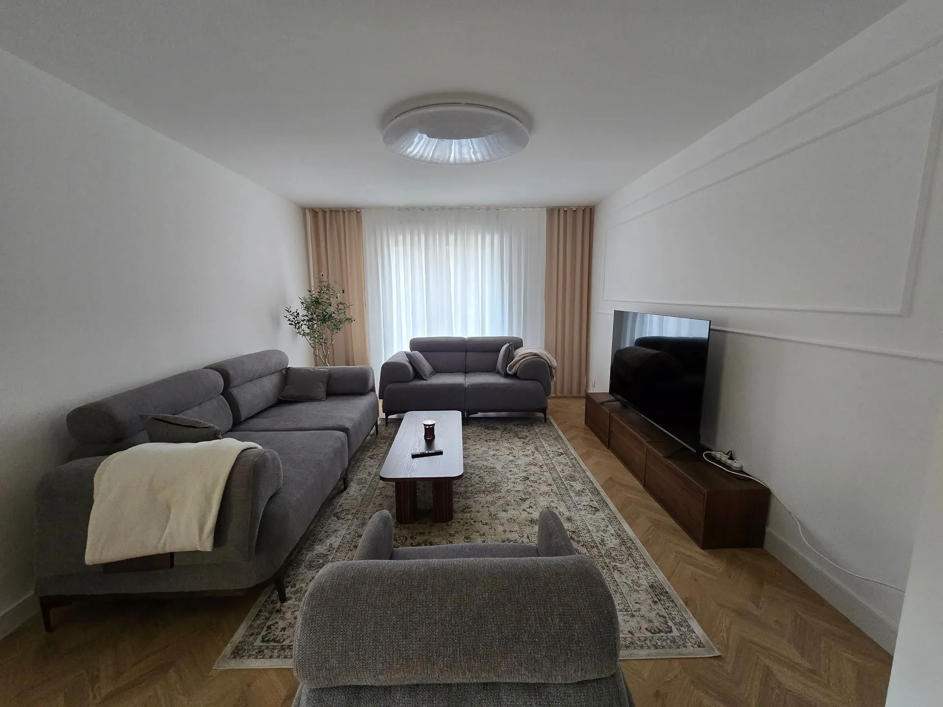 Salon d’un appartement rénové à Nyon, parquet en chevrons et murs blancs